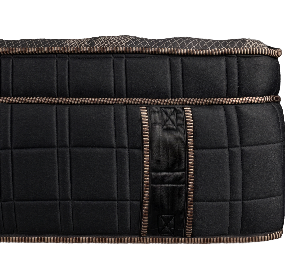 Close-up of a black padded suitcase with brown and beige striped piping and a handle.