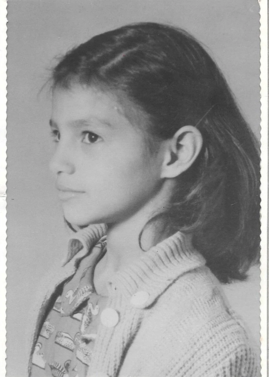 Black and white portrait of a young girl in profile, with shoulder-length hair, wearing a patterned shirt and sweater.
