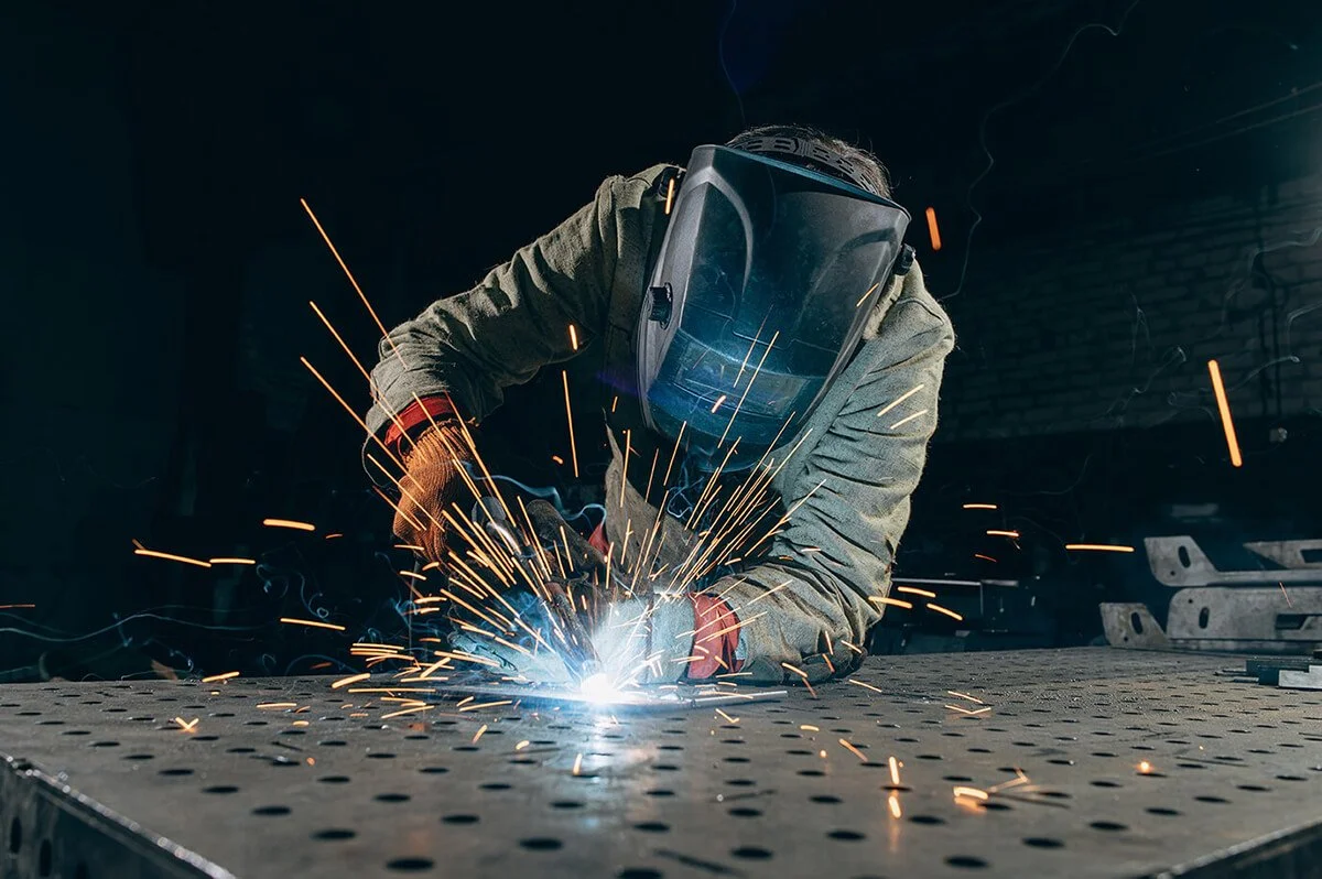 Midcoast Metal welder in protective clothing welds metal parts in the workshop