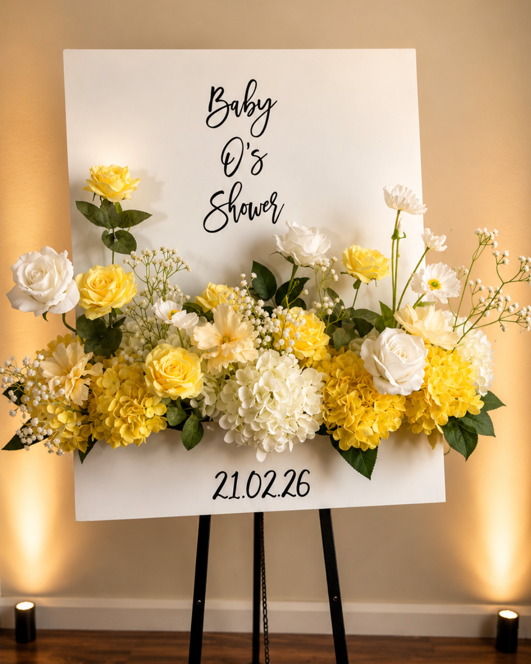Baby shower welcome display with white and yellow flowers and a personalised “Baby O’s Shower” sign.