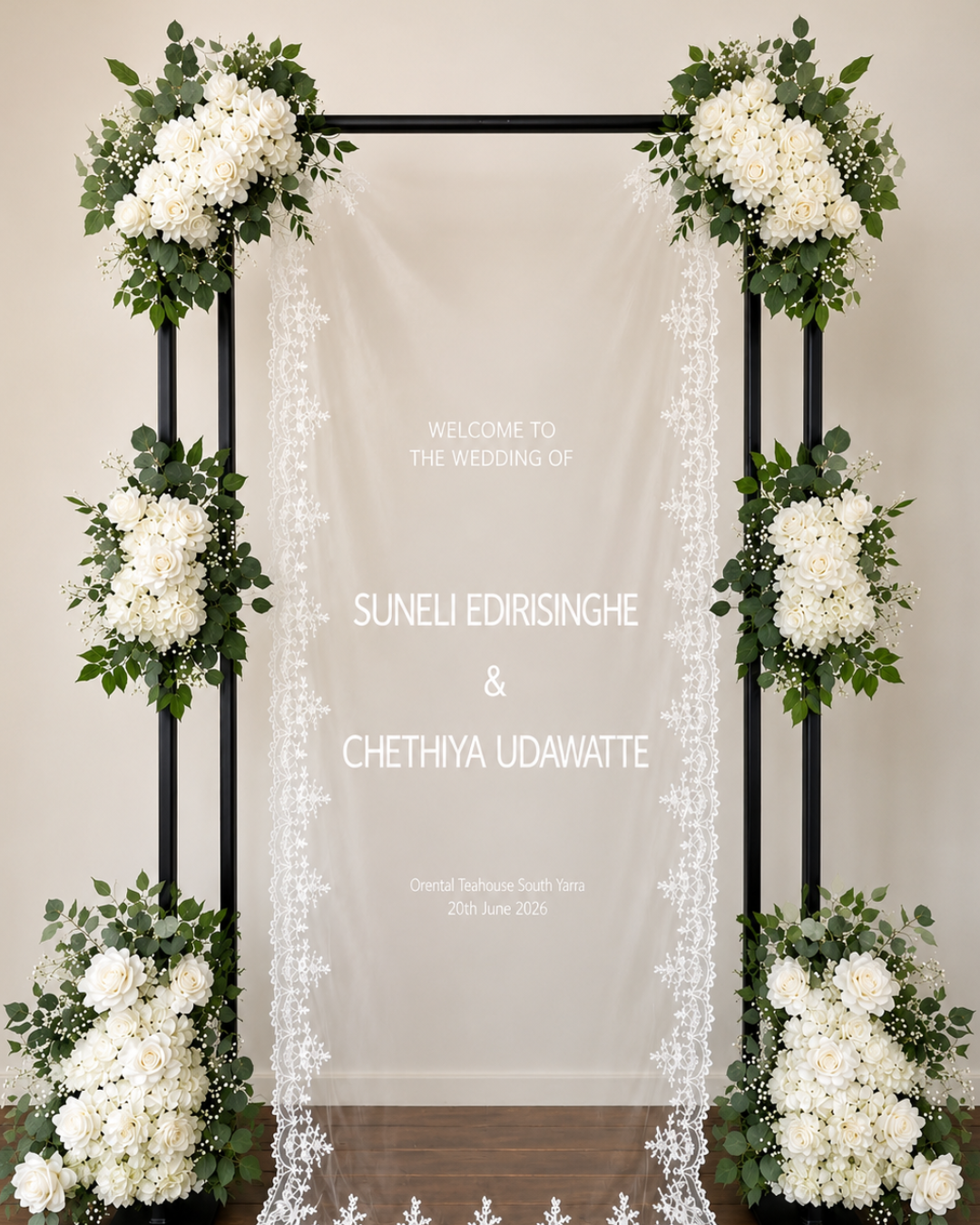 Wedding welcome sign with white roses and greenery, featuring wedding details and names on a sheer fabric backdrop.
