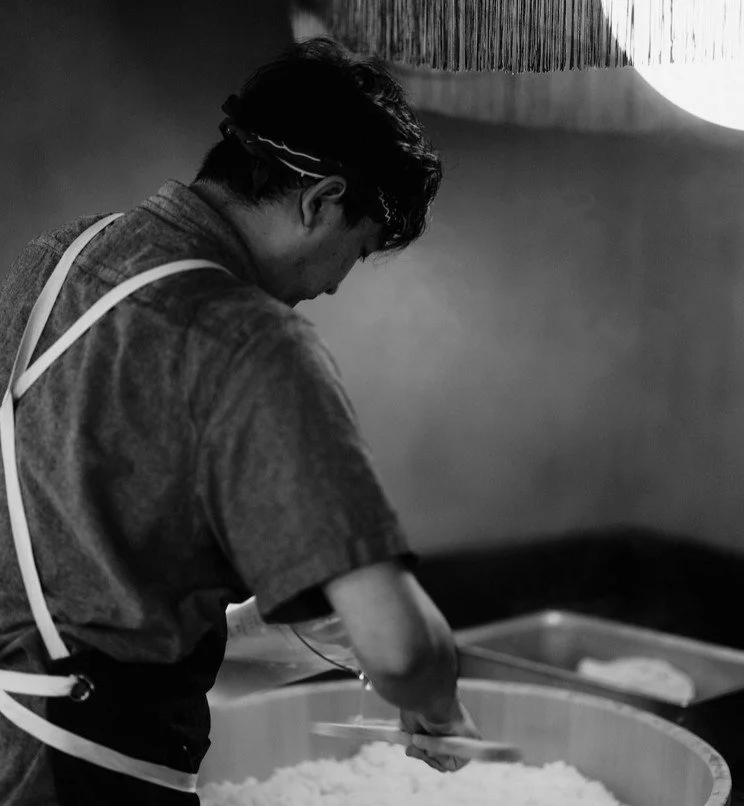 A person preparing food, possibly rice, in a traditional kitchen setting.
