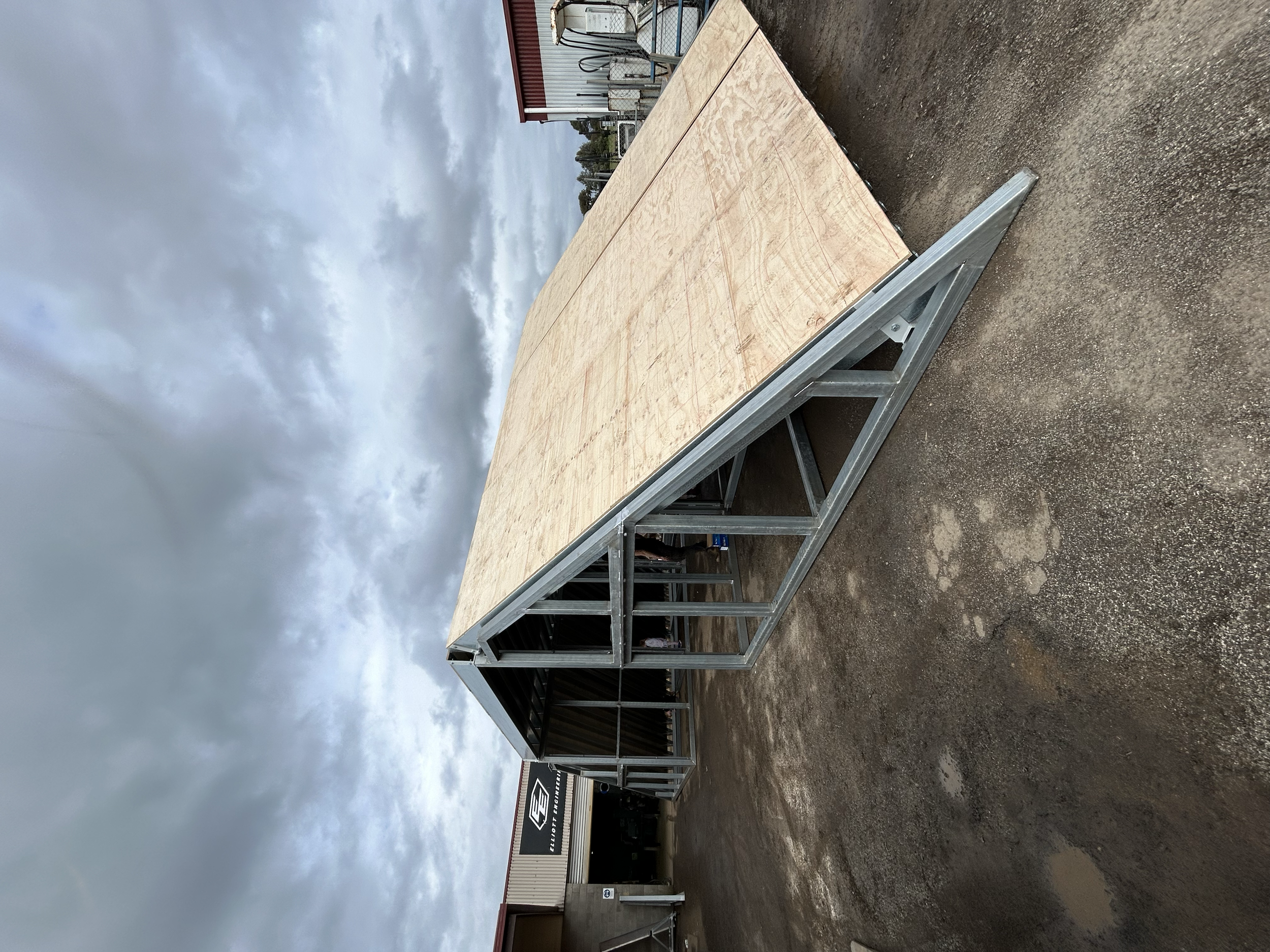 Exterior view of an industrial or commercial building with a metal frame structure and a sign reading Elliott Engineering