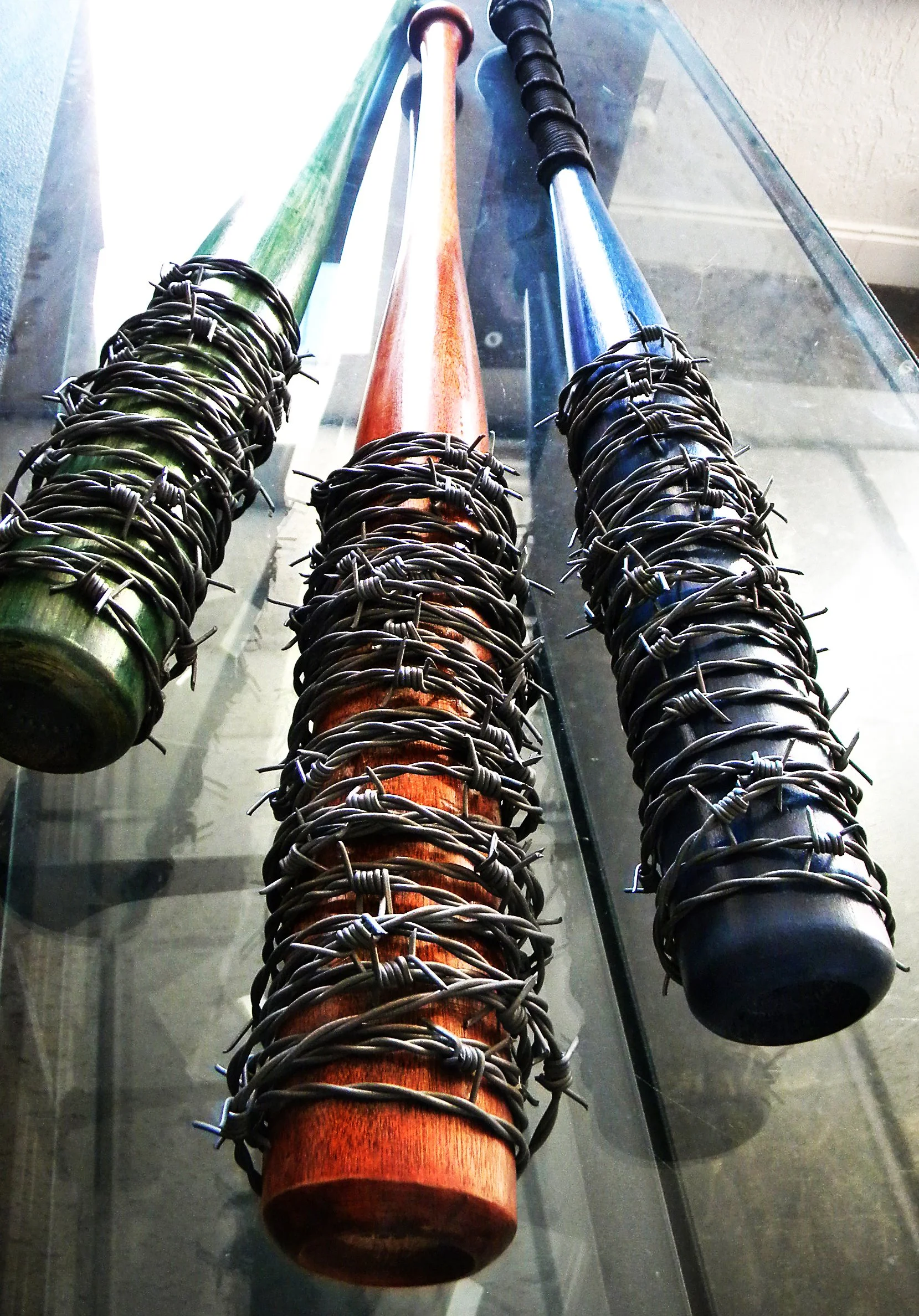 Three wooden bats, each painted and wrapped with barbed wire.