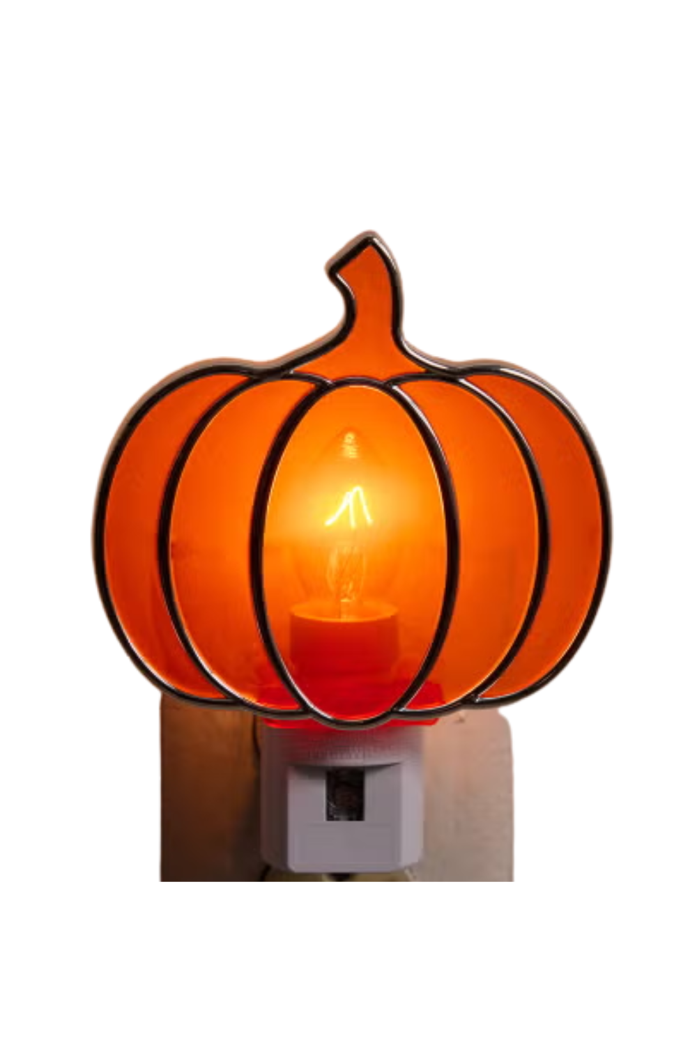 A pumpkin-shaped lamp with a glowing light inside, designed like a Halloween decoration, placed on a power outlet.