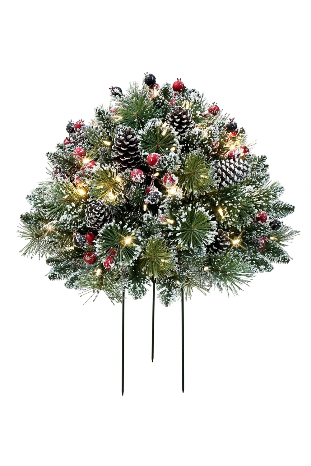 Decorative Christmas centerpiece with pine branches, pinecones, red berries, white snow-like accents, and warm white lights on a stand.