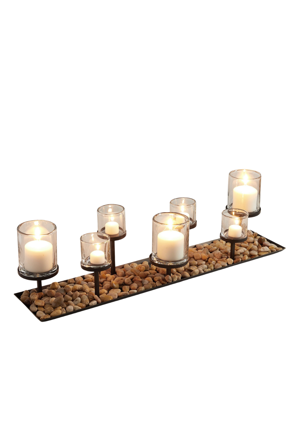 Decorative candle holder with six lit candles on a bed of small pebbles.
