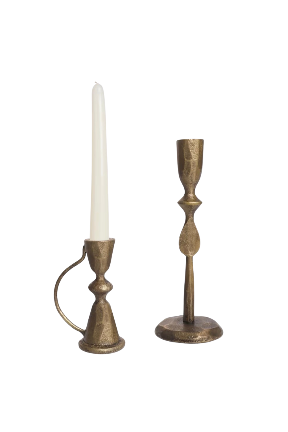 Two decorative candlestick holders, one with a tall white candle and one empty, made of gold-colored metal with a textured finish.