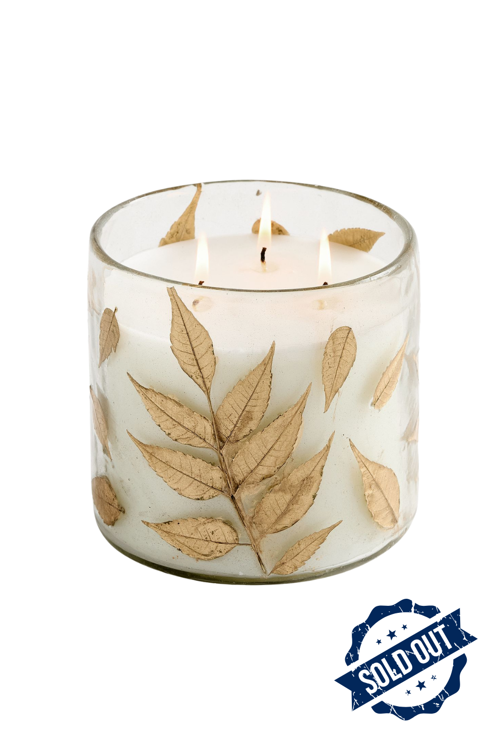 A white scented candle in a glass holder decorated with dried beige leaves, with three flames burning at the top, and a 'sold out' stamp in the bottom right corner.