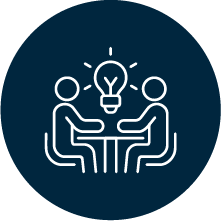 Two people sitting at a table, exchanging ideas, with a lightbulb above them symbolizing a new idea or brainstorming.