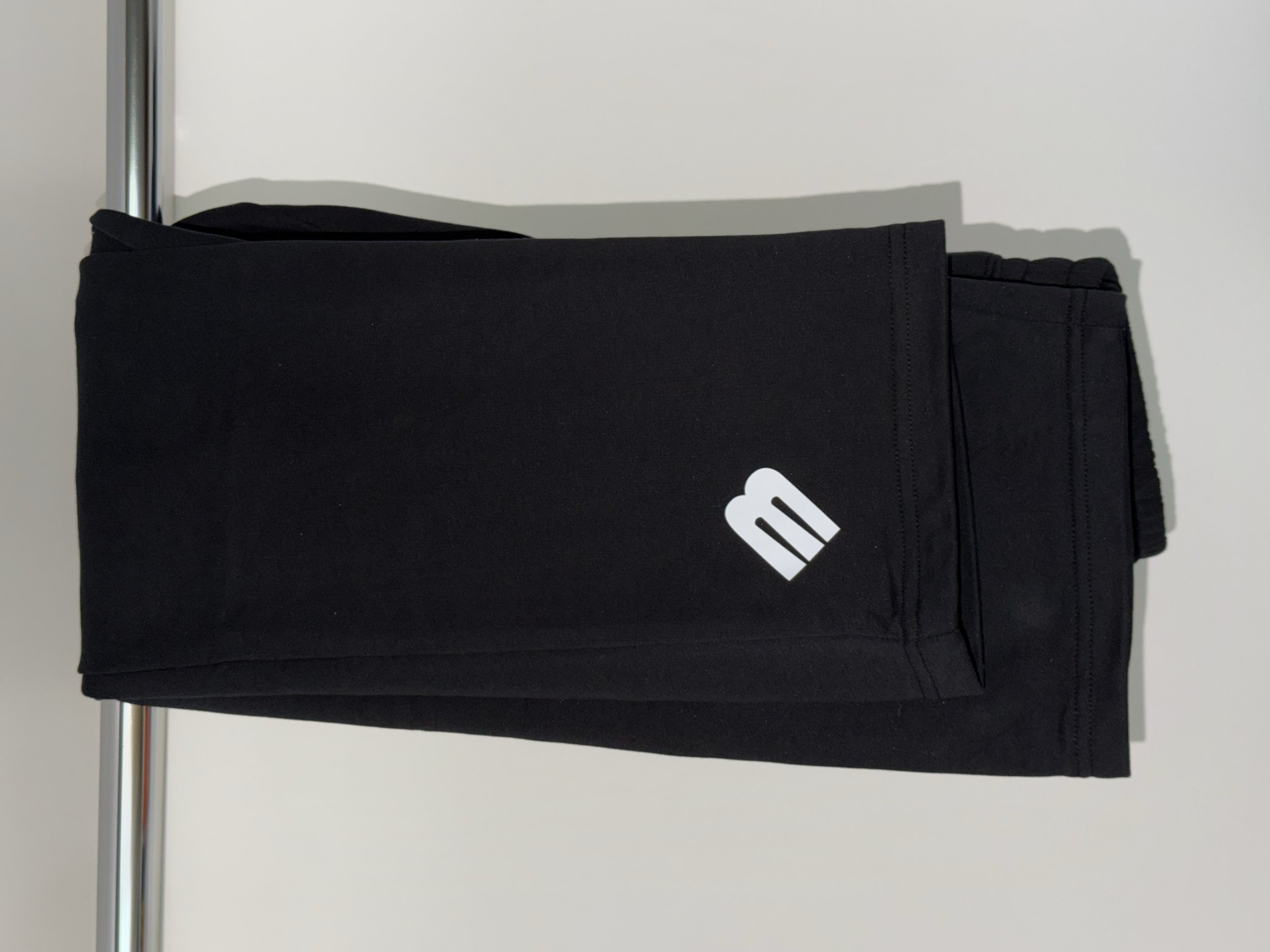 Black cloth bag hanging on a metal rod against a plain white wall
