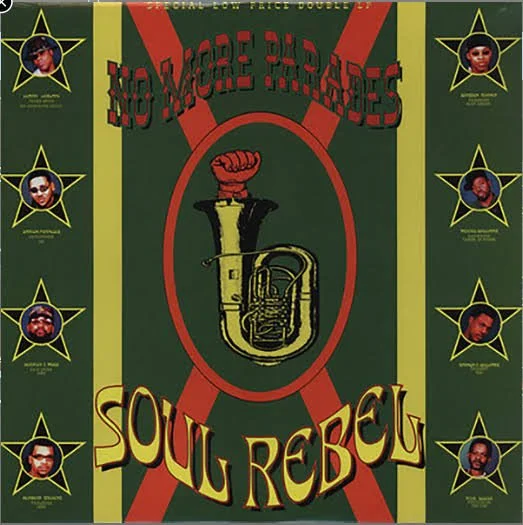 Album cover with a dark green background, featuring stylized text and a central illustration of a brass instrument with a clenched fist on top. The title reads 'No More Parades' at the top and 'Soul Rebel' at the bottom, with yellow and red accents. The border has star-shaped images of band members' portraits in each corner.