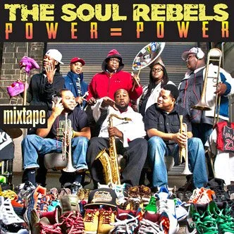 The Soul Rebels band with multiple members holding various musical instruments, surrounded by sneakers, in front of a backdrop with the text 'The Soul Rebels Power = Power' and 'mixtape'.