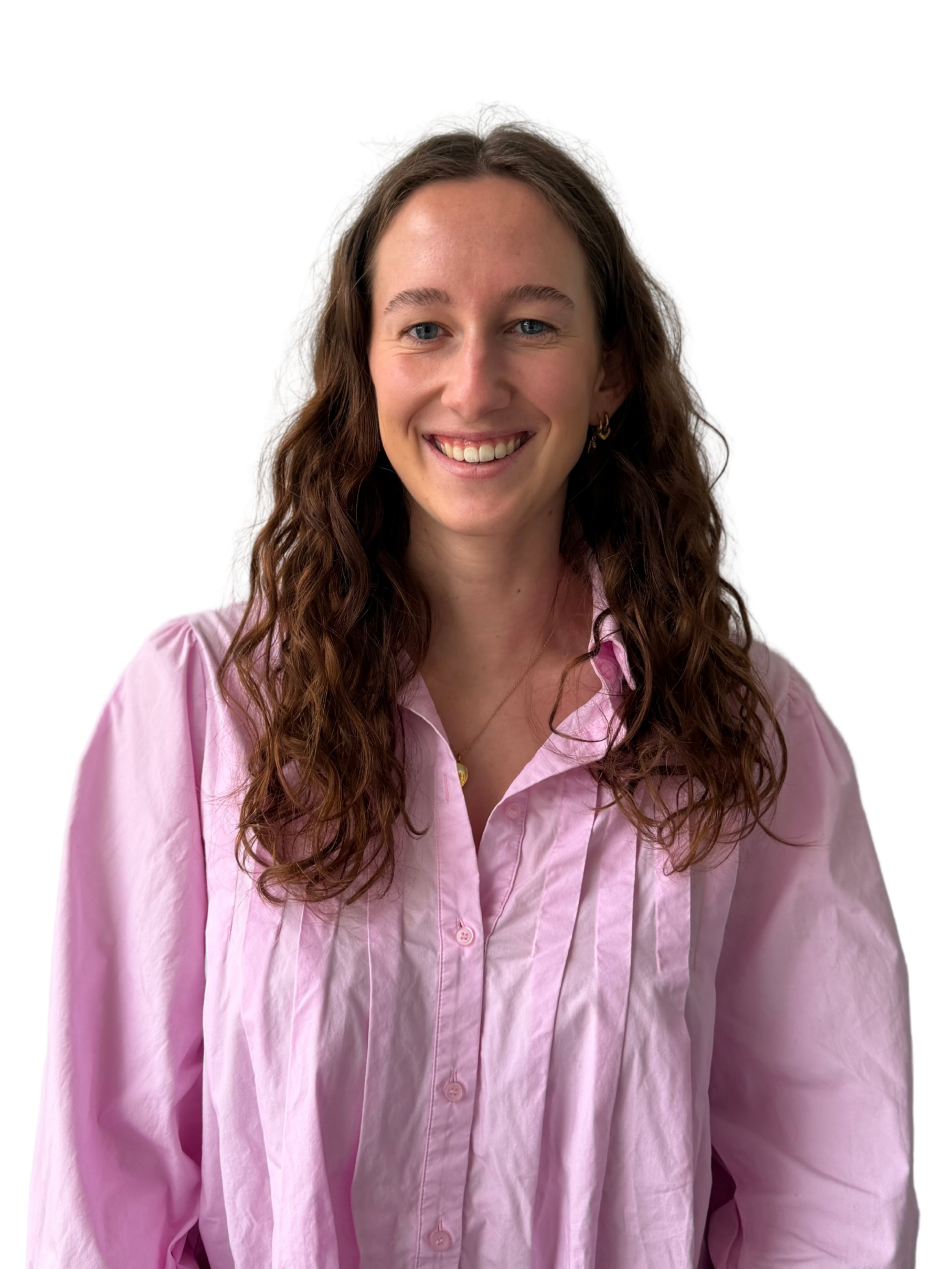 A woman with long, wavy brown hair smiling, wearing a pink button-up shirt and gold earrings, against a plain white background.