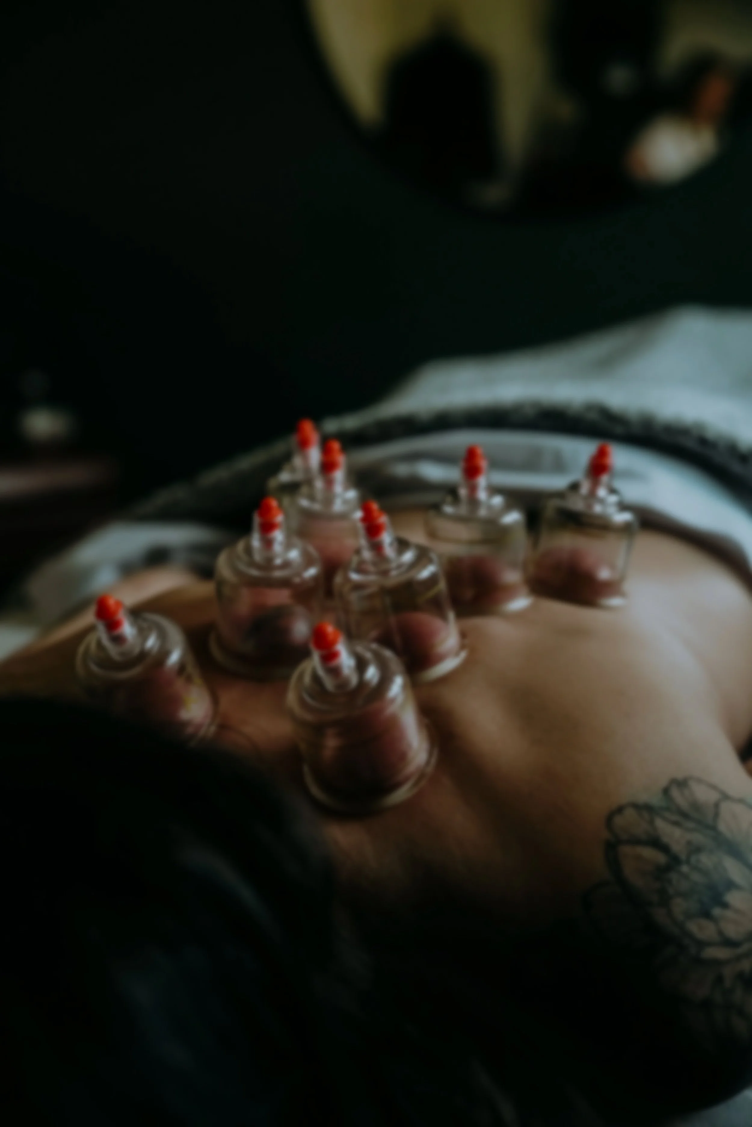 A person's arm with resin-filled capsules or bottles, with some tattoos visible on the forearm, and a black and gray sleeve or shirt sleeve partially visible.