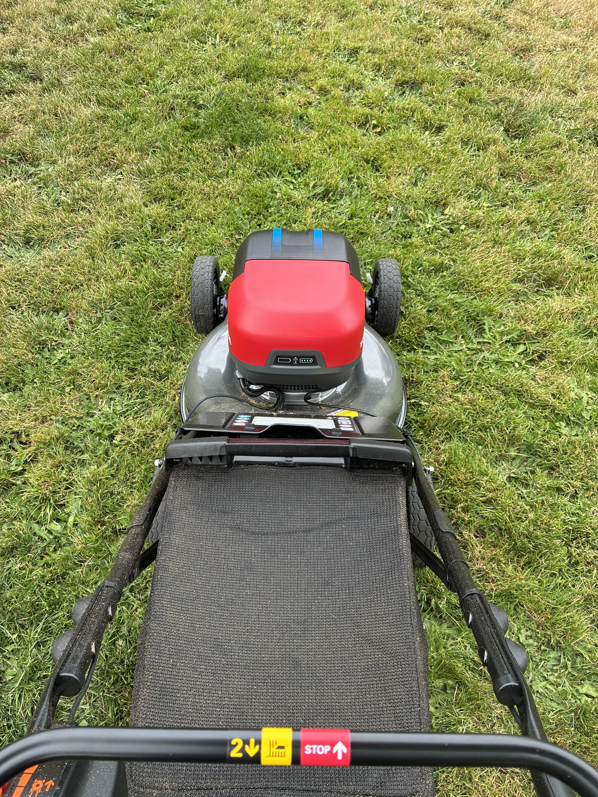 View from the back of a lawn mower facing forward on a grassy lawn.