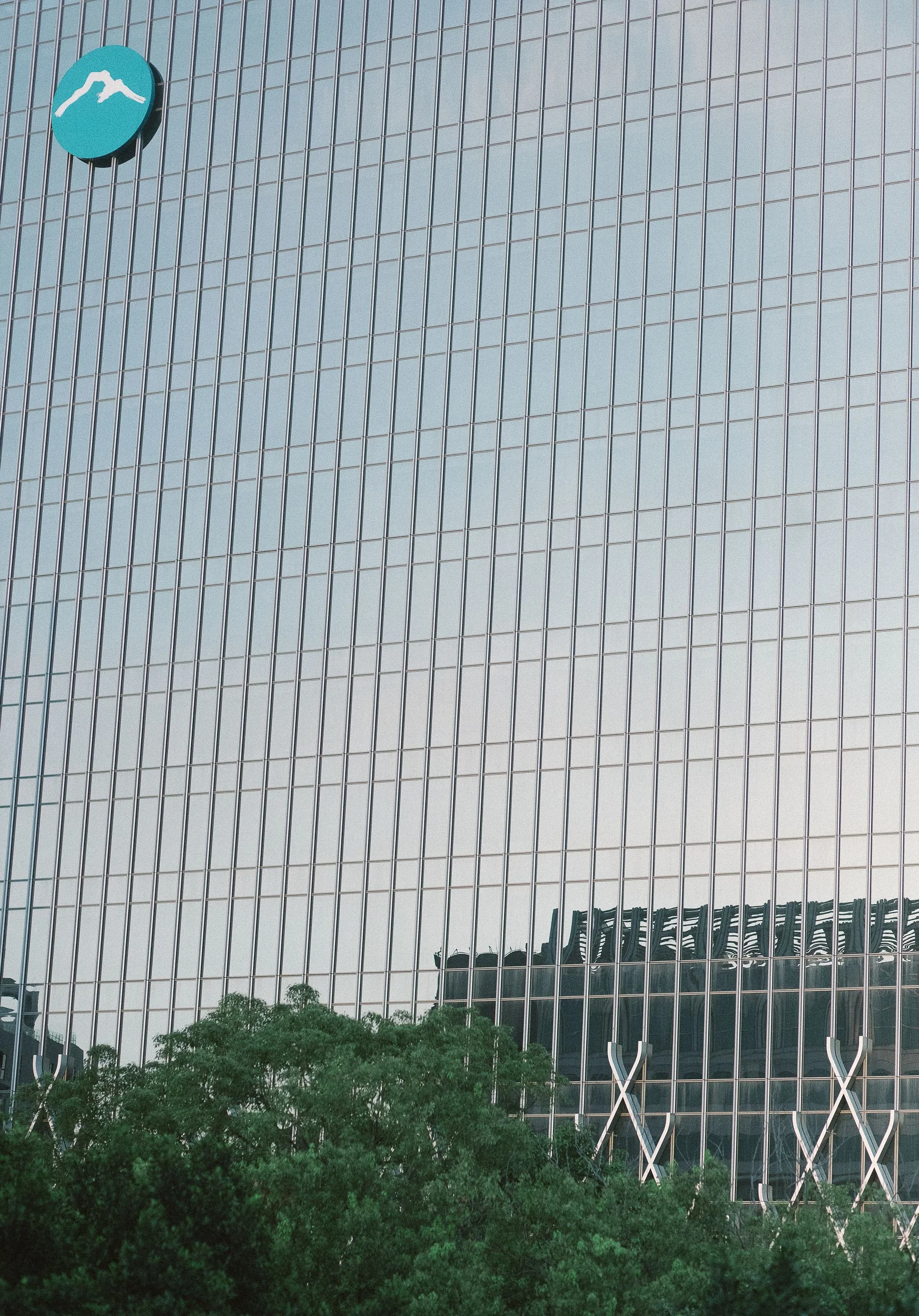 Modern building with a glass facade reflecting the sky and trees, visible in the lower part of the image.