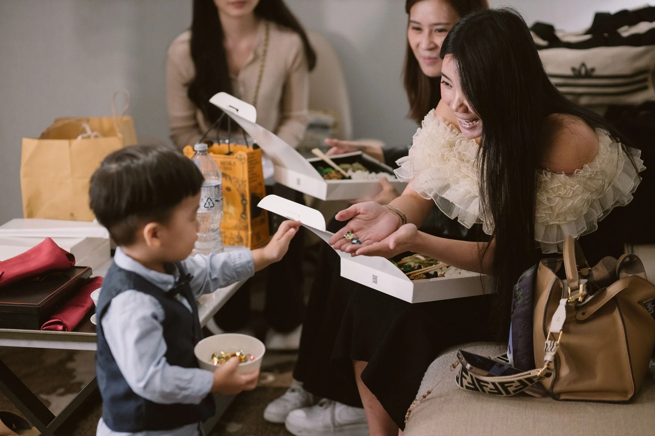 A group of people giving food and gifts to a young boy at a celebration or gathering.