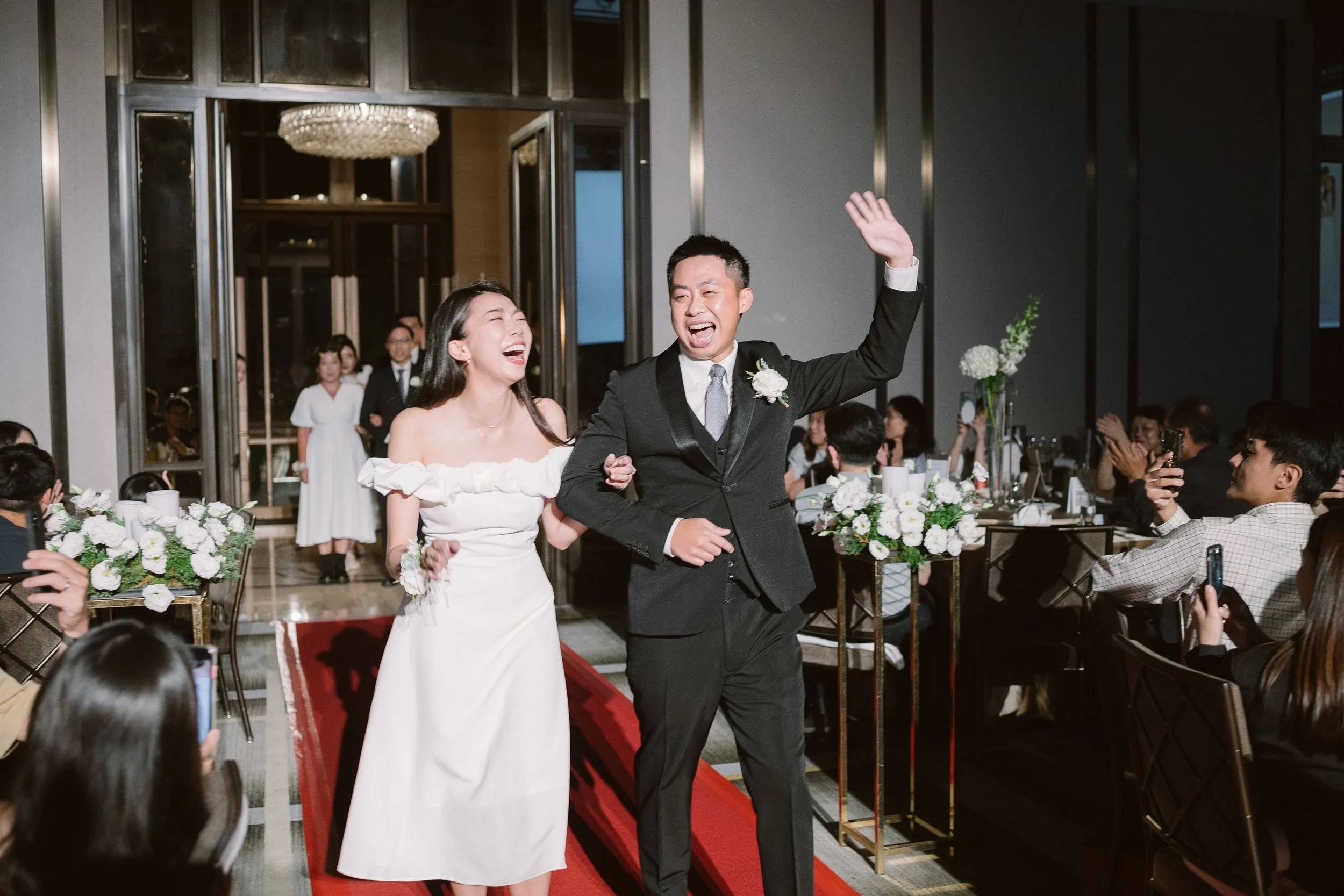 A bride and groom are walking down the aisle at their wedding reception, smiling and celebrating.