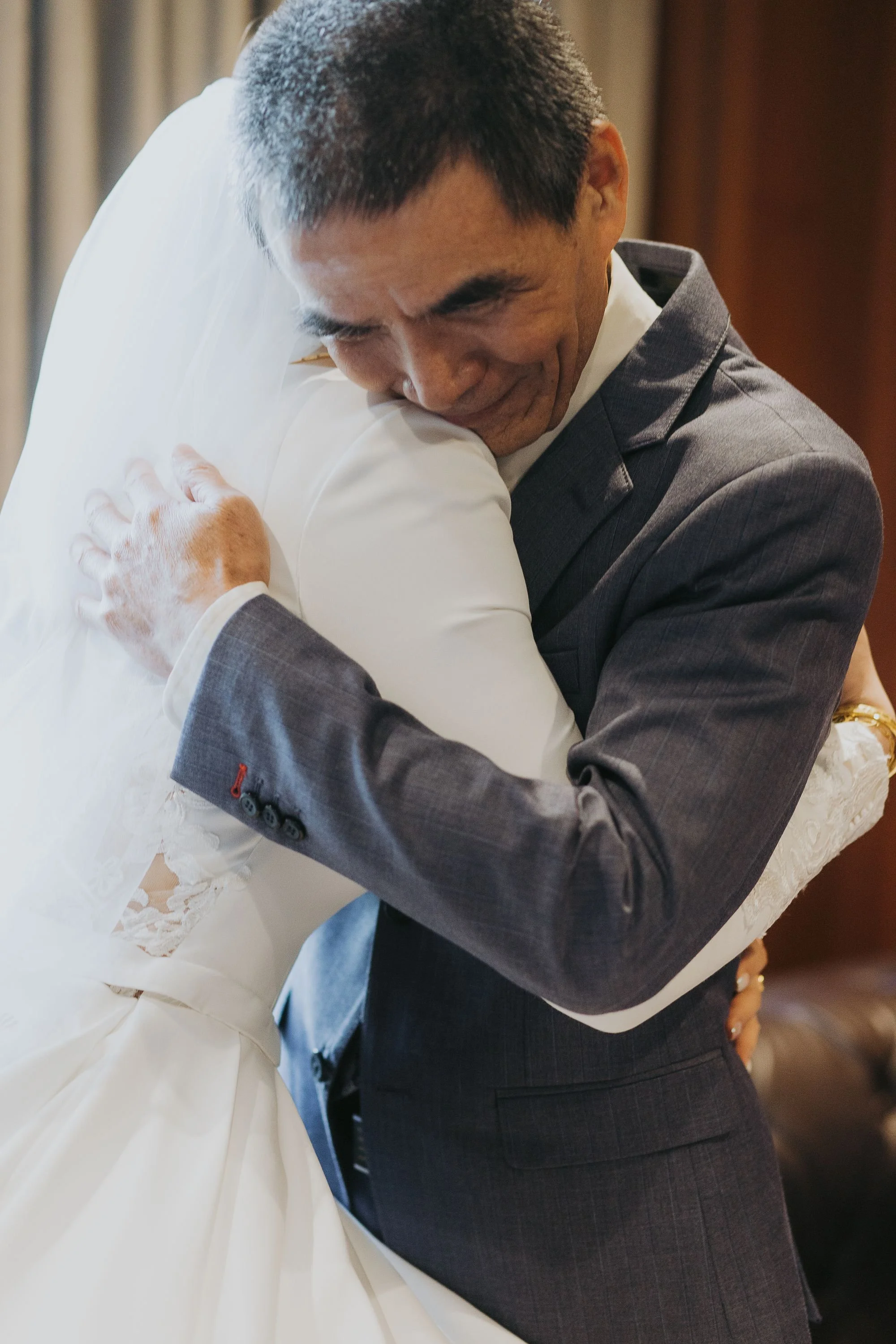 Two men, one in a white suit and the other in a gray suit, hugging each other warmly.