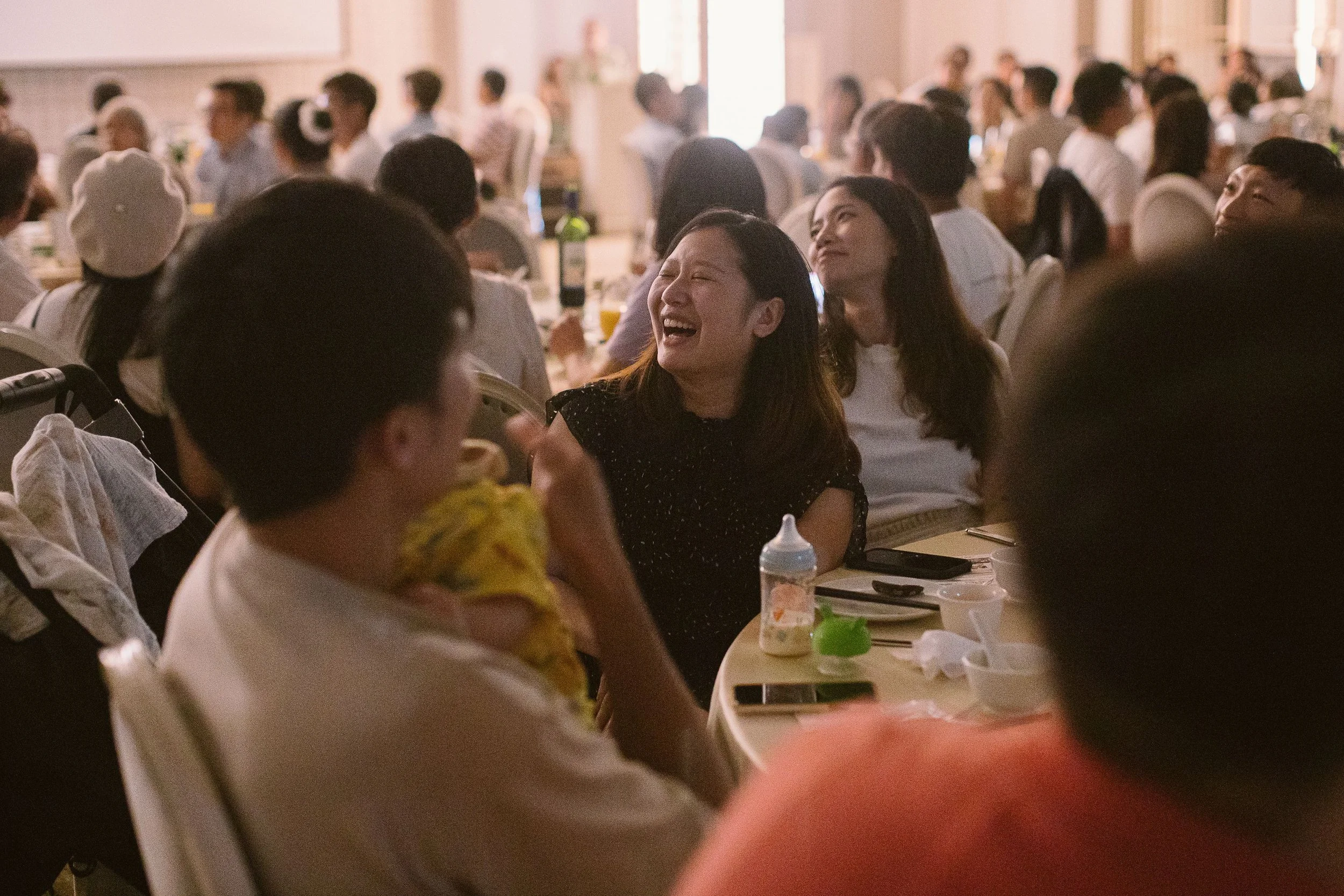 People sitting at tables in a banquet hall, smiling and enjoying a social event.