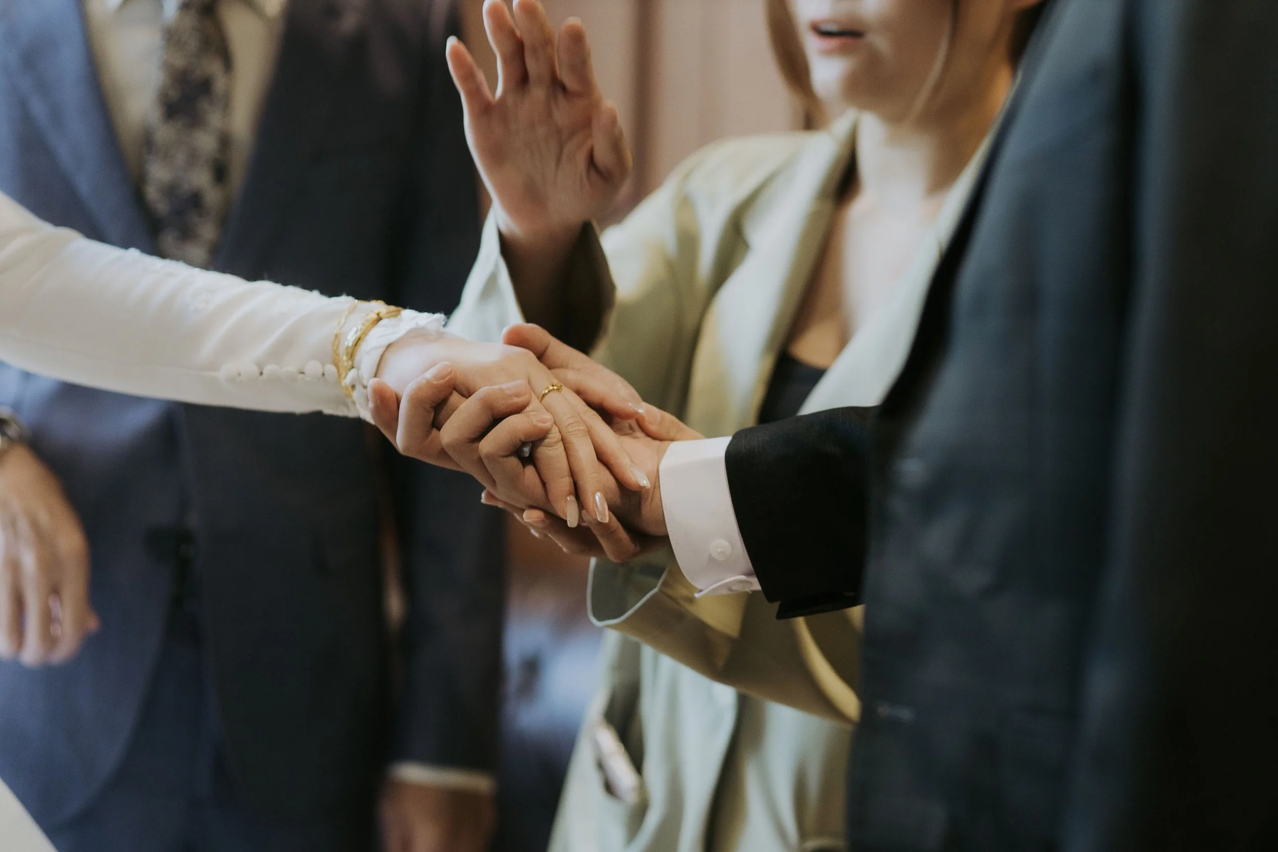 A close-up of a wedding ceremony showing a bride and groom holding hands, with the bride giving a fist bump.