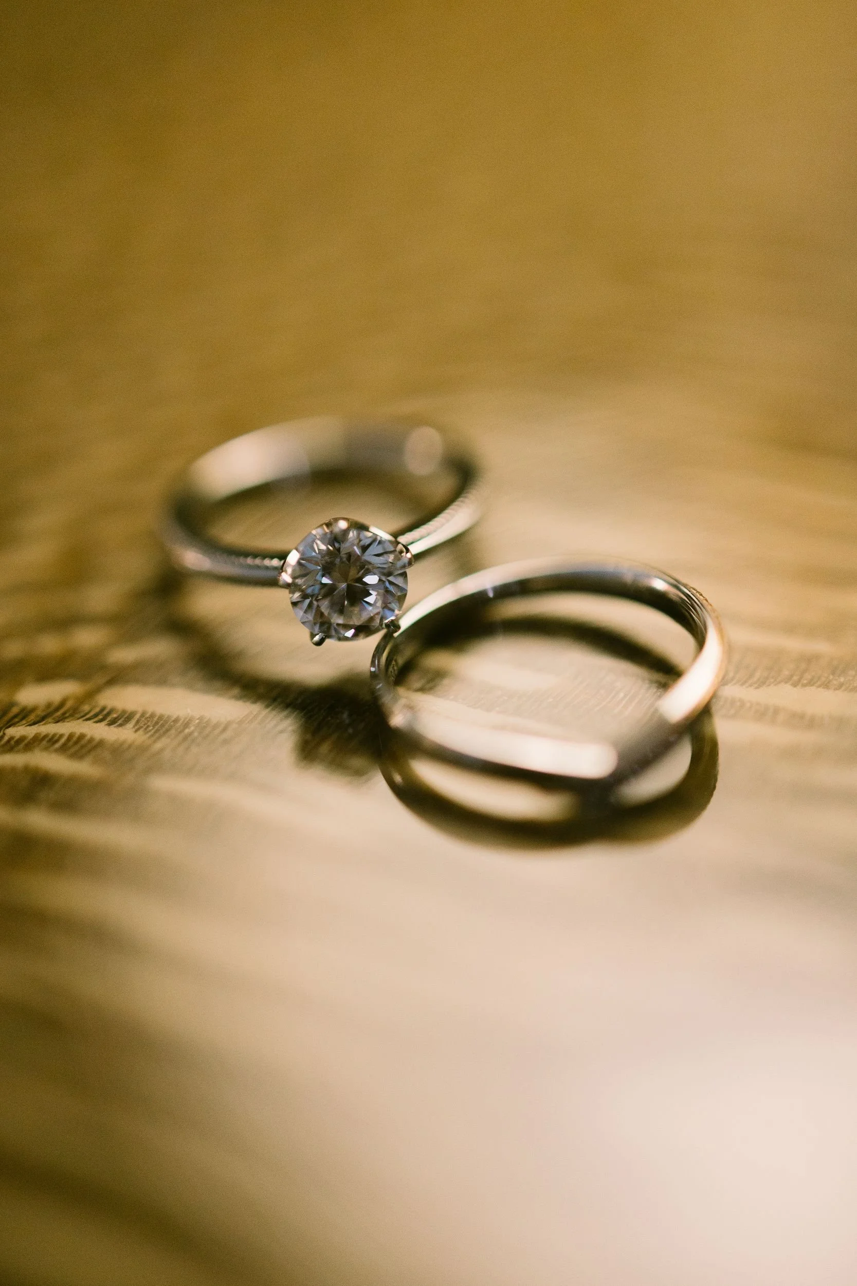 A close-up of three rings on a golden fabric surface, with one ring featuring a prominent diamond.