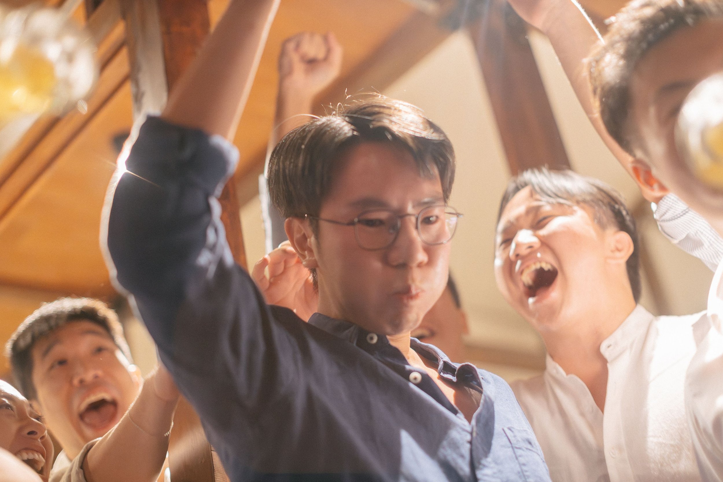 A group of people celebrating together, smiling and laughing, with their hands raised in excitement.