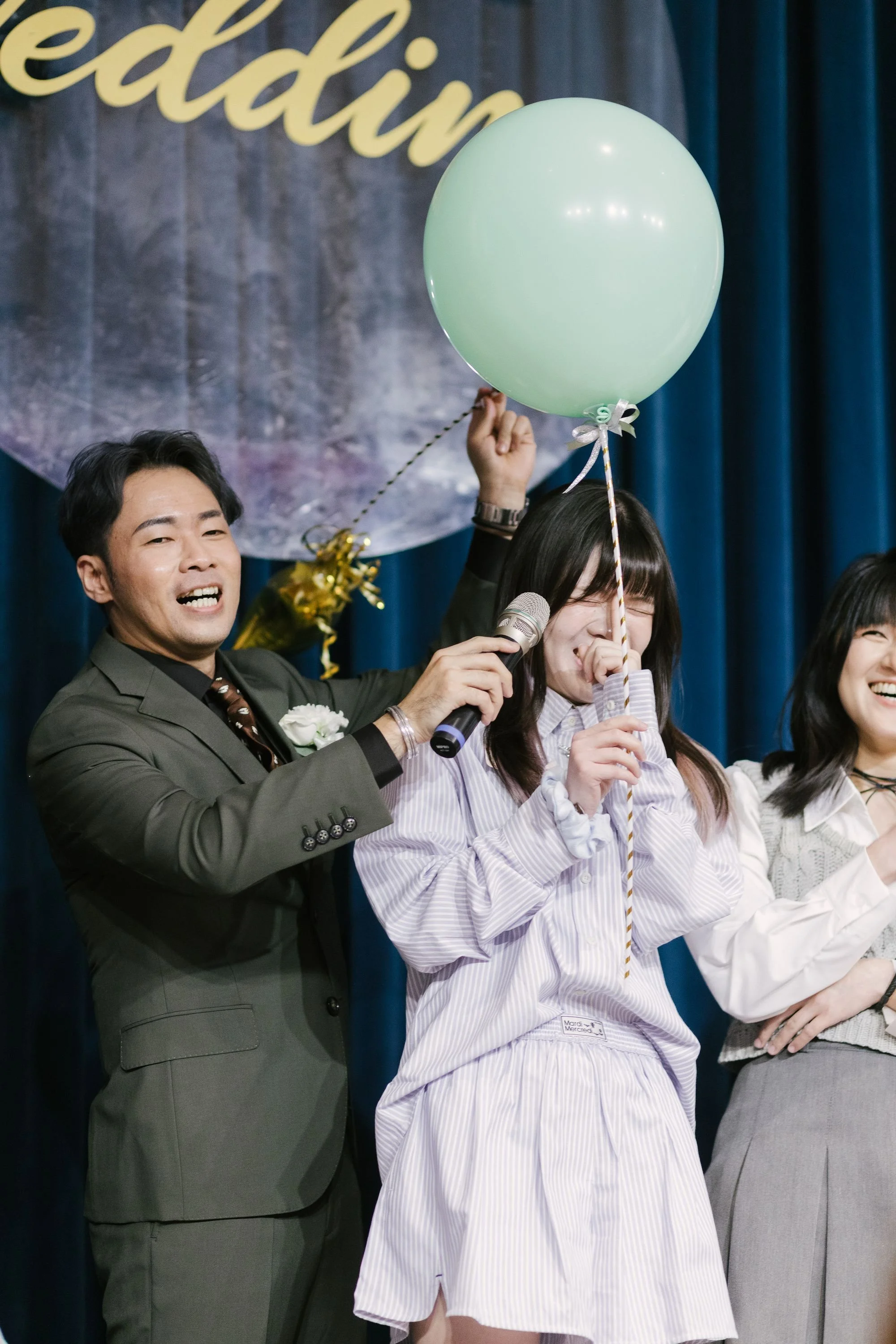 People on stage at a celebratory event, holding balloons and smiling.