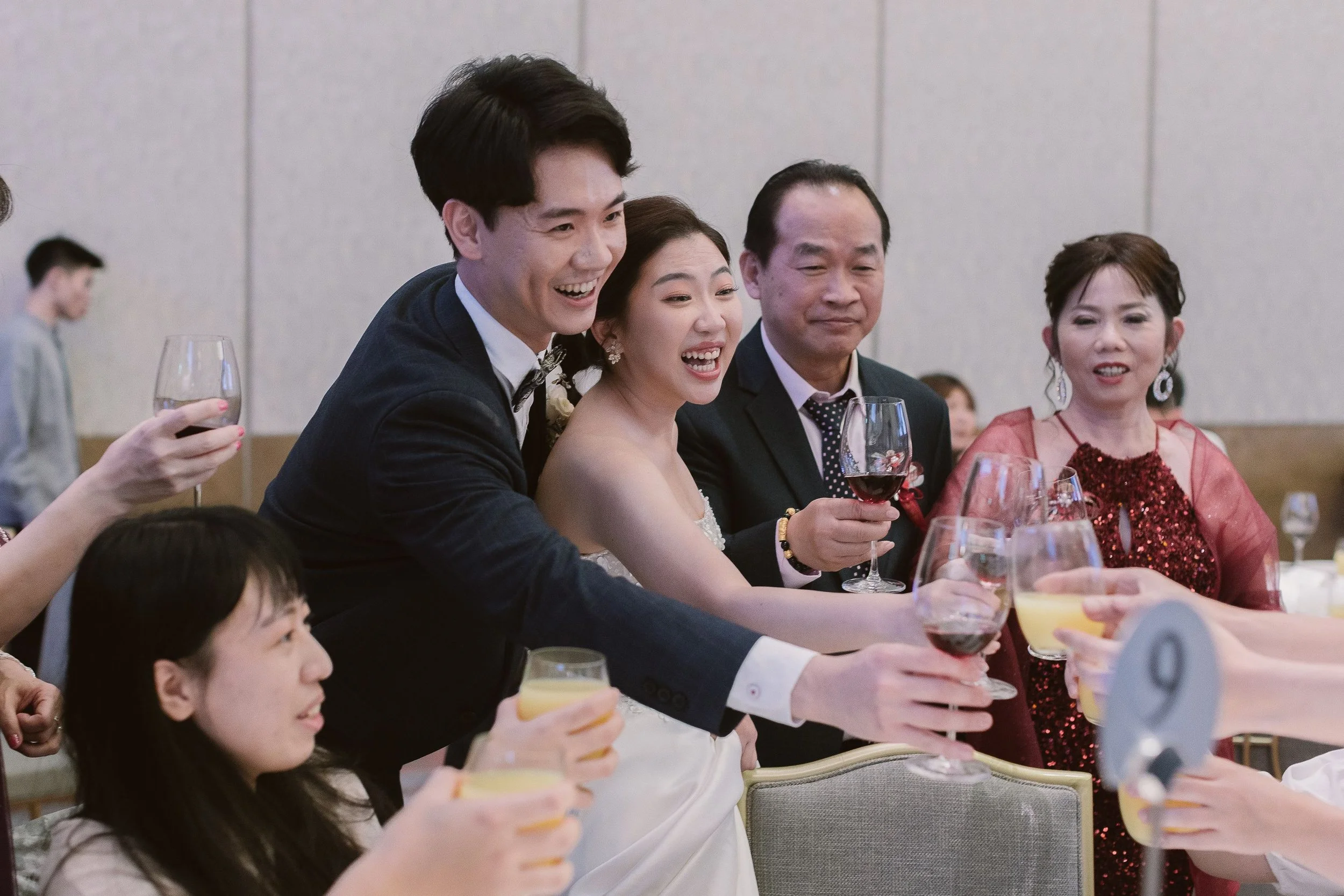 People dressed in formal attire at a celebration, holding glasses of wine and smiling.