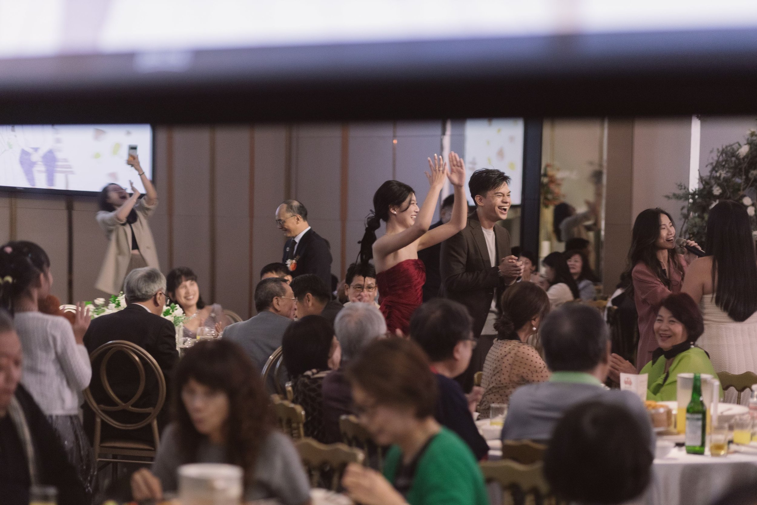 People in formal attire at a banquet, some smiling and clapping, others taking photos.