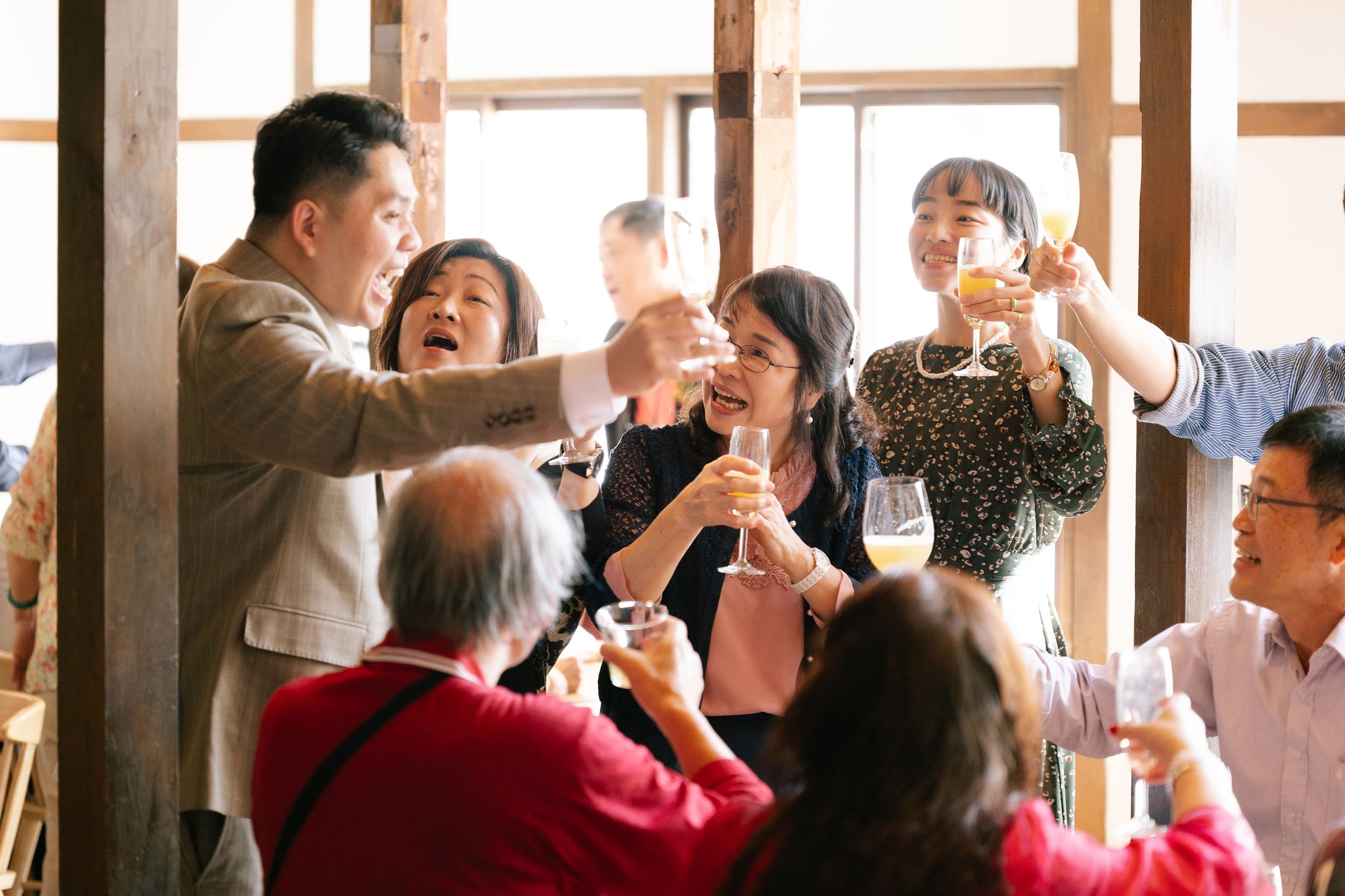 People celebrating with drinks at a social gathering in a bright indoor setting.