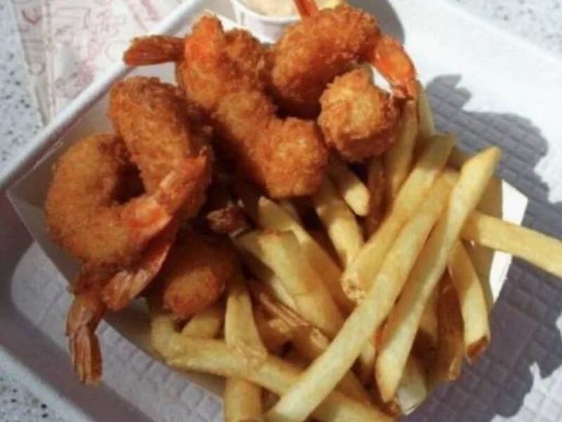 Fried shrimp and French fries served in a paper-lined cardboard tray.