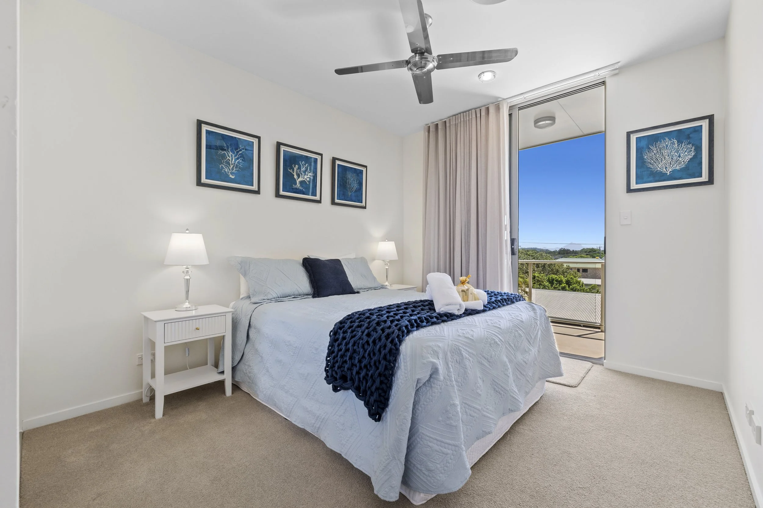 Queen guest bedroom with coastal styling, natural light and private balcony access at MING 3.