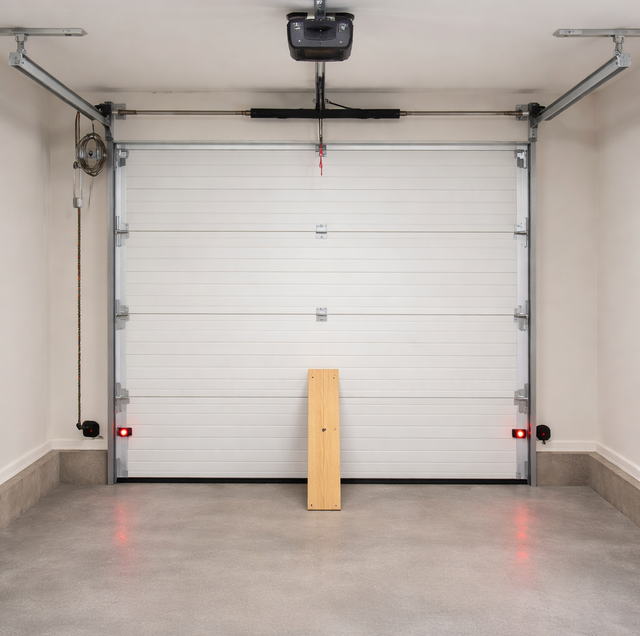landlord inspecting garage door spring and photo eye