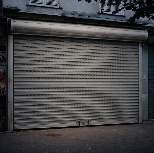 closed roll-up security grille revealing lit storefront display