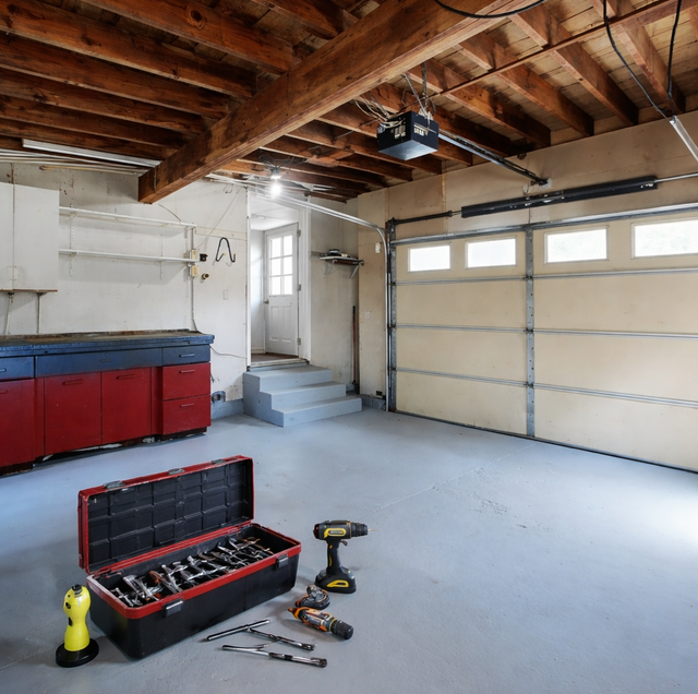 residential garage door technician inspecting springs with flashlight