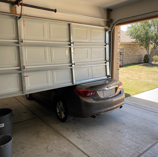silver sedan trapped beneath half-open garage door