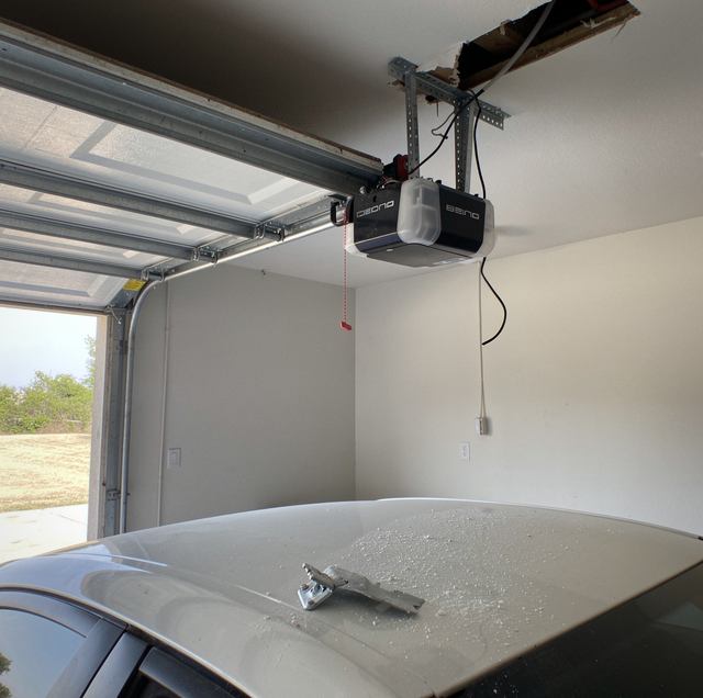 garage door opener motor hanging from torn ceiling bracket
