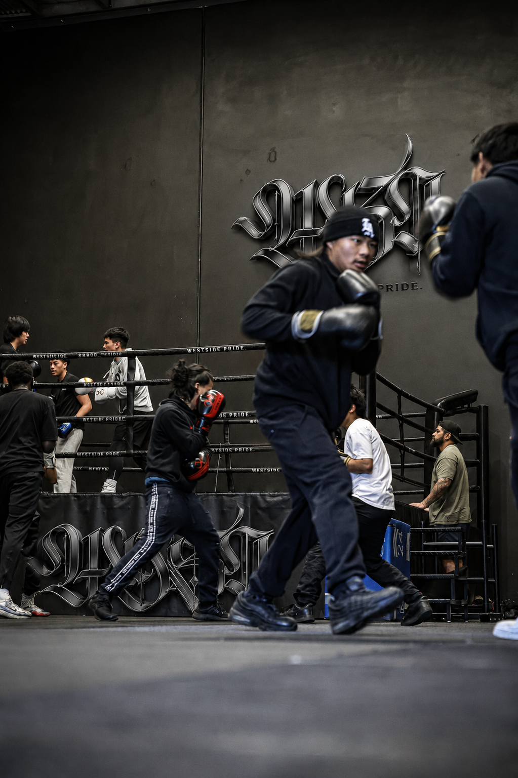 Boxers training and sparring in a gym with black walls and a large "Westsdie Pride" logo.