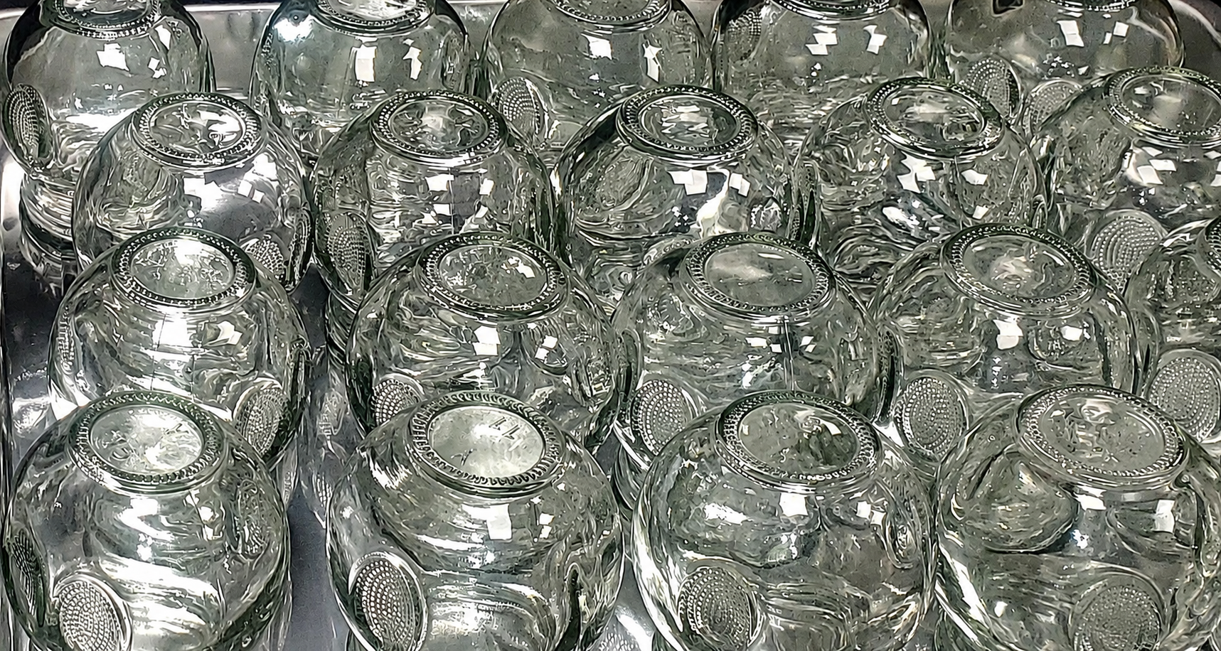 A collection of clear, empty glass therapy cups with decorative embossed patterns, arranged upside down.