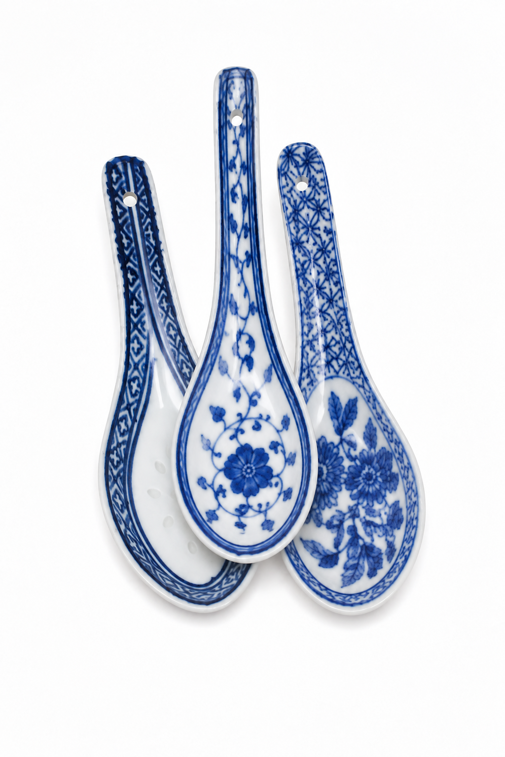Three blue and white ceramic spoons with floral and geometric patterns, arranged overlapping on a white background.
