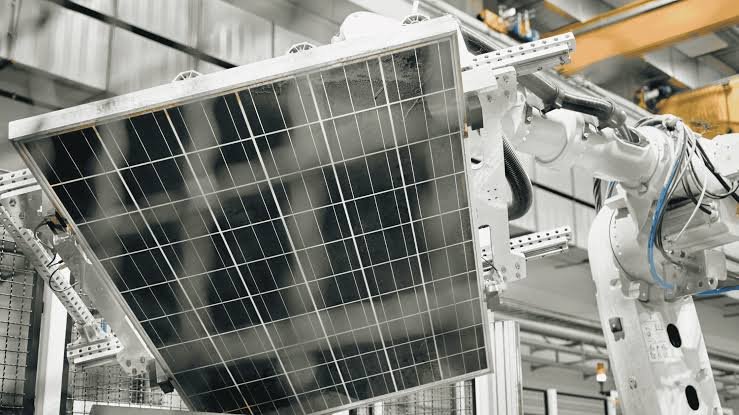 Industrial robotics arm installing or maintaining a large solar panel in a manufacturing or testing facility.
