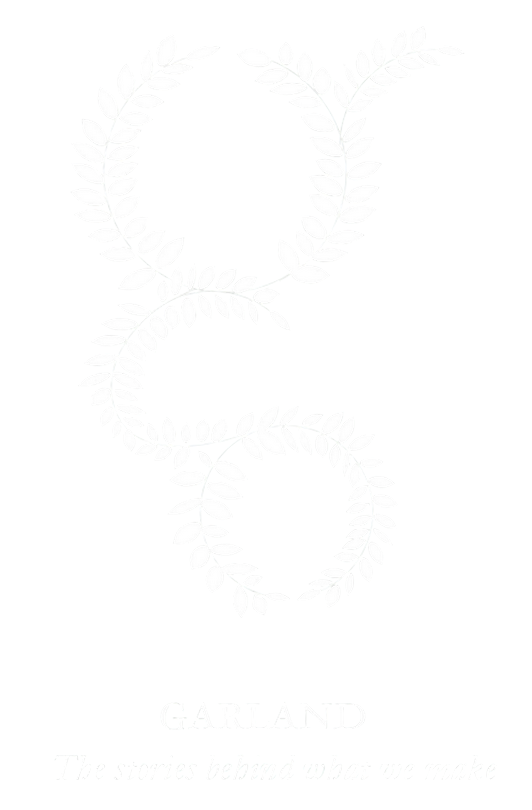 White leafy garland forming the shape of an ampersand on a black background with the text 'GARLAND' and the subtitle 'The stories behind what we make' below.