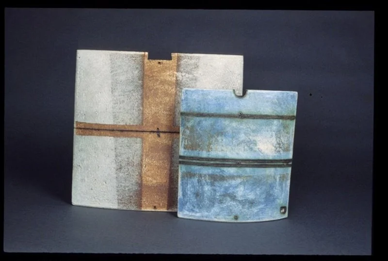 Two weathered, rusty metal parts with a blue and white finish, placed on a dark background.