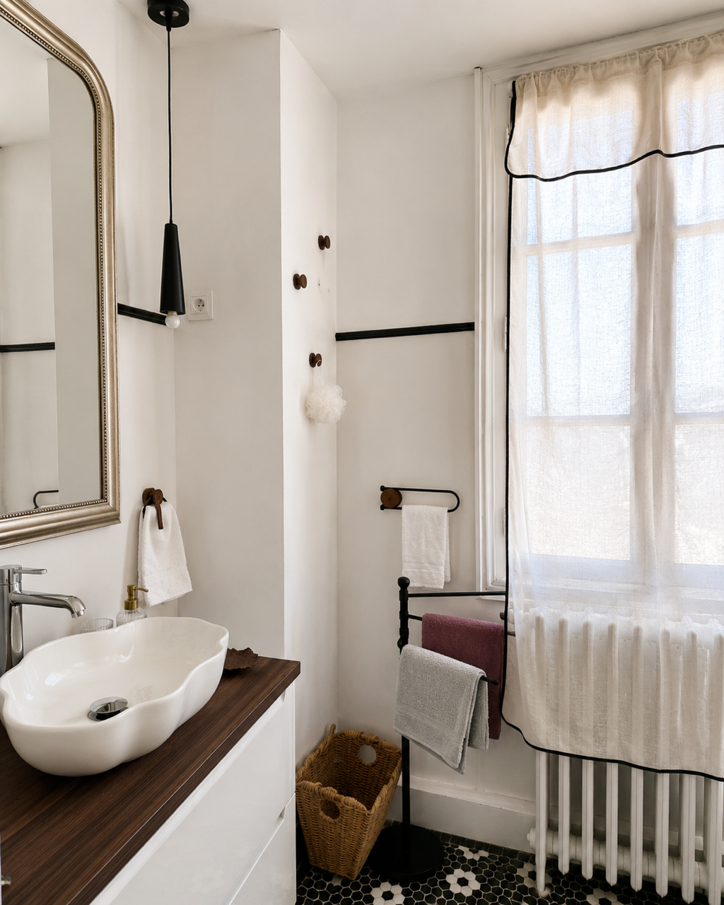 Salle de bain 1er étage Horizon avec un miroir, un évier en surface de bois, des serviettes, une lampe suspendue, un panier en osier, et une fenêtre avec rideaux blancs.