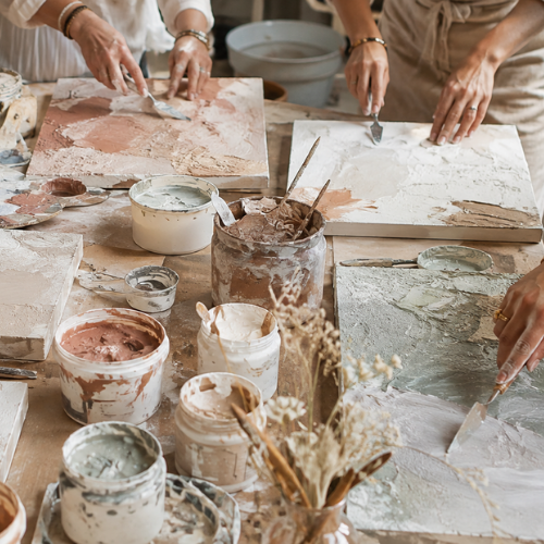 Groupe de personnes travaillant sur des œuvres en céramique avec des pinceaux et des pots de peinture lors d'un brunch atelier Maison Tourterelle