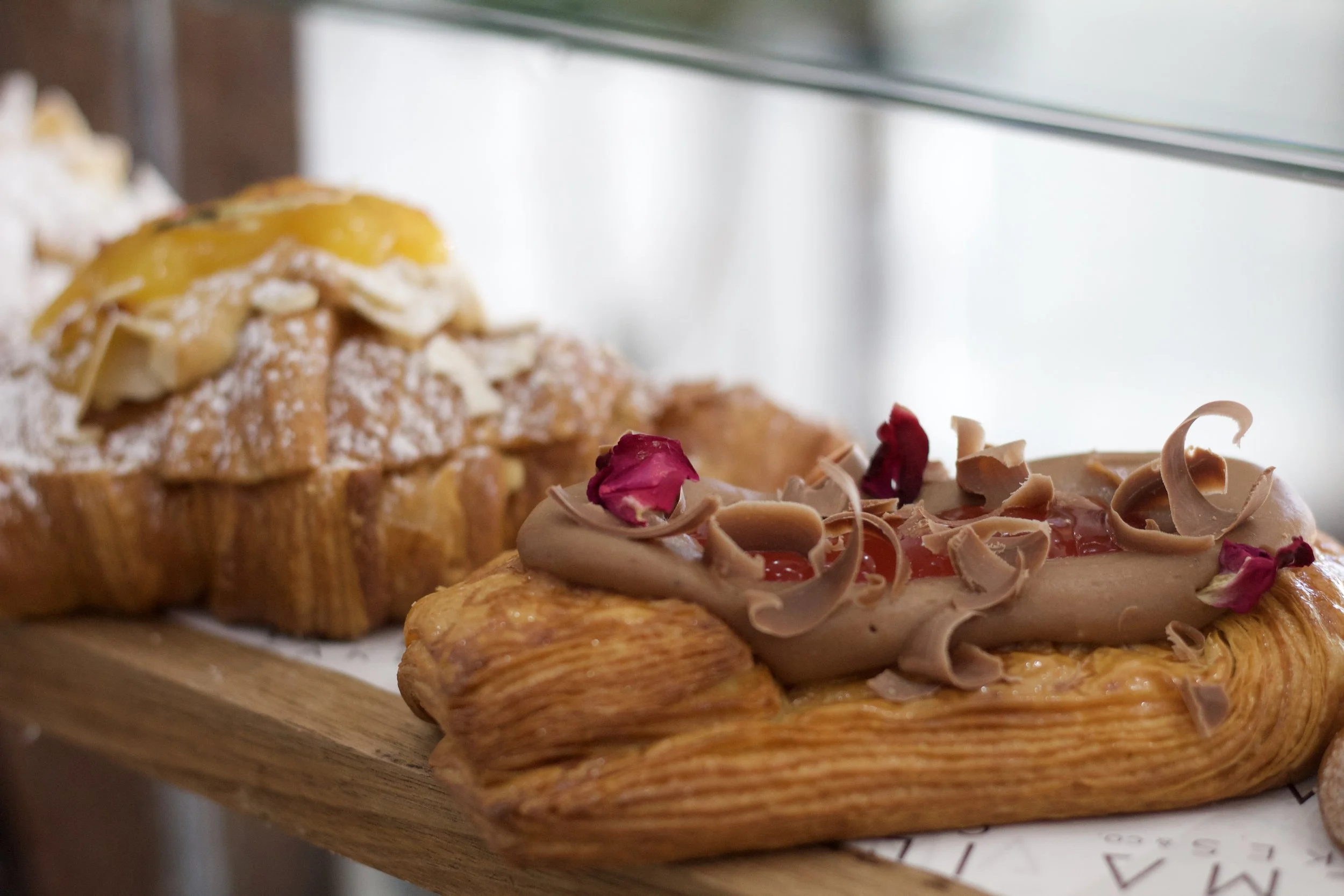 Assorted pastries with various fresh toppings, including lemon, caramel displayed on a wooden surface. French pastries are only Thursday and Friday as they are made from scratch in store using traditional techniques