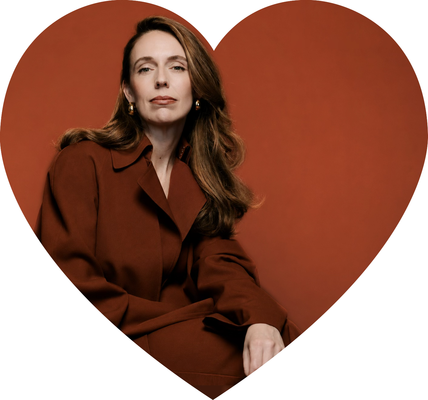 A woman with long wavy brown hair, wearing a dark red blazer, sitting against a matching red background, inside a large heart shape outline.