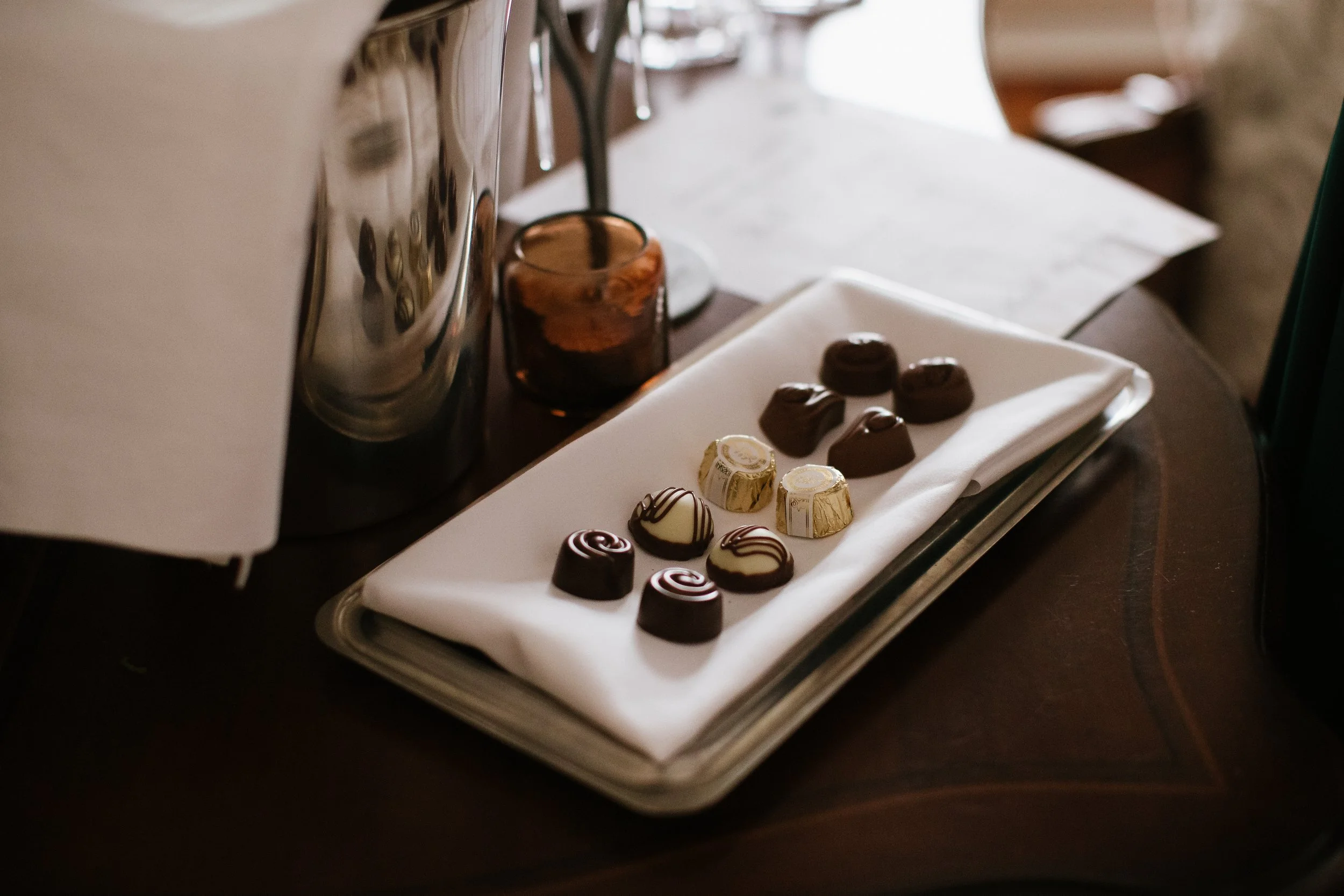 A tray of assorted chocolates with different shapes and drizzled designs, placed on a white napkin.